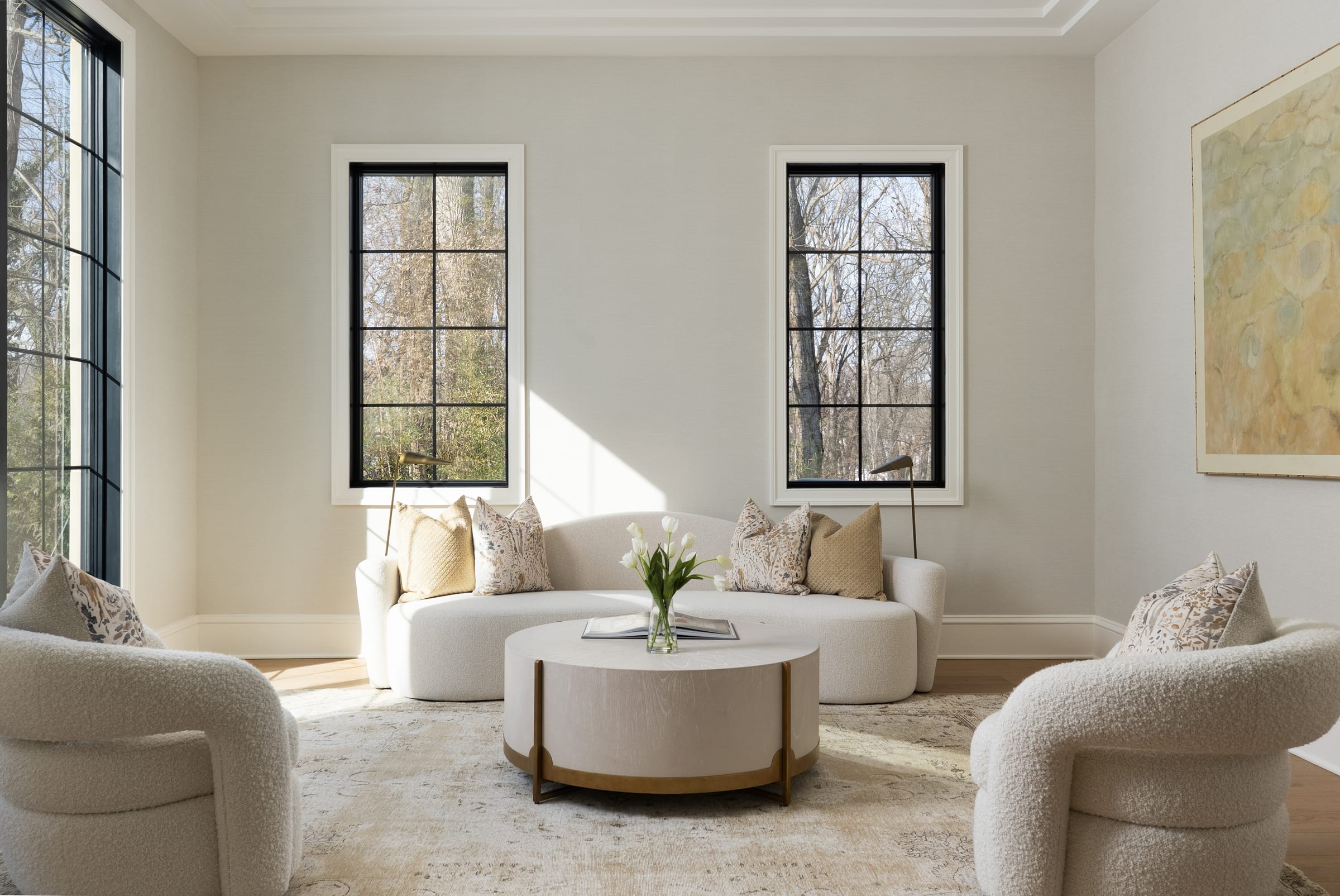 Sun-filled sitting room with bouclé armchairs and black steel-frame windows